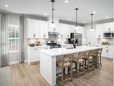 Modern kitchen featuring white cabinetry, stainless steel appliances, and a spacious island with barstool seating at 1312 Piper Glen Dr, Sunset Beach, NC 28468