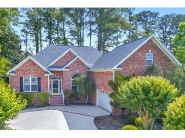 Charming brick home with mature landscaping, a well-manicured lawn, and an attached two car garage at 154 Windsor Circle Sw, Ocean Isle Beach, NC 28469
