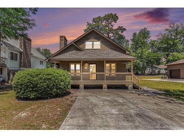 Charming home featuring a cozy porch, wood siding, and well-maintained landscaping and large driveway at 2191 Liberty Circle, Little River, SC 29566