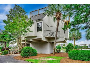 Unique elevated home with a rooftop deck surrounded by lush greenery and a tranquil waterside view at 24 Frigate Ct., Pawleys Island, SC 29585