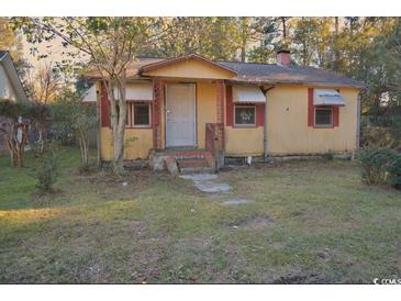 Quaint single-story home featuring a covered porch and mature trees in a serene, wooded setting at 414 E Wine St., Mullins, SC 29574