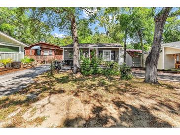 Charming cottage exterior with mature trees, a red door, and dark shutters at 6001-N74 South Kings Hwy., Myrtle Beach, SC 29575