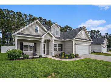 Charming home with a well-manicured lawn, lush landscaping, and a two-car garage at 630 Heartwood Dr., Conway, SC 29526