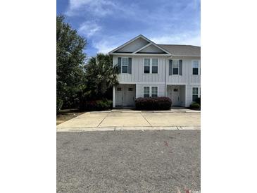 Charming townhome with white siding, double-hung windows, and inviting curb appeal surrounded by lush greenery at 730 Madiera Dr. # 101, North Myrtle Beach, SC 29582