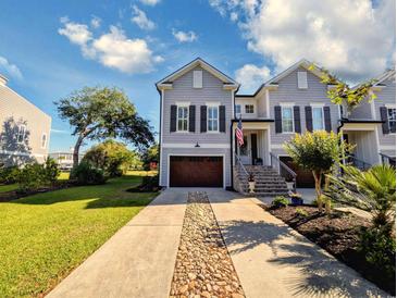 Charming two-story home features a brown garage door, stone details, and an inviting front porch at 80 Landing Dr. # 80, Pawleys Island, SC 29585