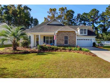 Charming home featuring stone accents, a well-manicured lawn, and an inviting front porch at 100 Woodlyn Ave., Little River, SC 29566