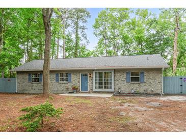 Charming single-story brick home with blue shutters and a well-maintained front yard surrounded by mature trees at 1111 King St., Myrtle Beach, SC 29577