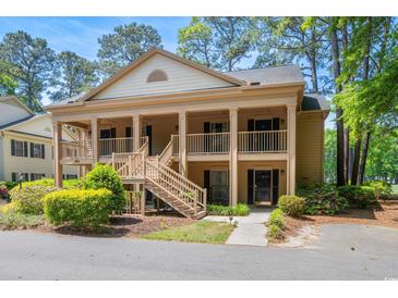 Charming two-story condo with a covered front porch and wooden stairs, surrounded by lush landscaping at 141-4 Weehawka Way # 4, Pawleys Island, SC 29585