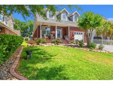 Charming brick home featuring a manicured lawn, beautiful landscaping, and a welcoming front porch with rocking chairs at 2019 Ye Olde Kings Hwy., North Myrtle Beach, SC 29582