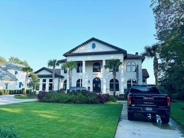 Elegant two-story home featuring a manicured lawn, palm trees, and a classic architectural design with prominent columns at 4110 Gray Heron Dr., North Myrtle Beach, SC 29582