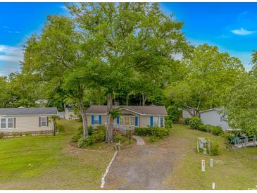 Charming home with a tan exterior, blue shutters, and a large shady tree in the front yard at 930 S Marlin Circle, Murrells Inlet, SC 29576