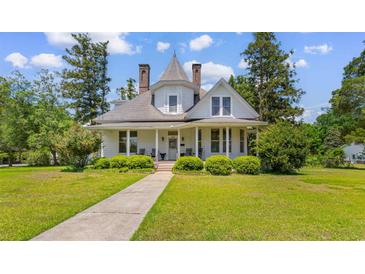 Charming two-story home with landscaped yard, inviting porch, and distinctive architectural details at 118 Ford Ave, Mullins, SC 29574