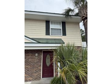 Inviting townhouse with a red front door, brick facade, and lush palm trees at 1432 Highway 544 # B2, Conway, SC 29526