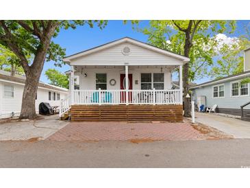 Charming cottage with a covered porch and red brick parking pad, perfect for relaxing outdoors at 6001 South Kings Hwy., Myrtle Beach, SC 29575