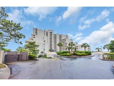 Beautiful building with landscaping, driveway, and sky background, with palm trees and garden areas at 101 Ocean Creek Dr. # Dd7, Myrtle Beach, SC 29572