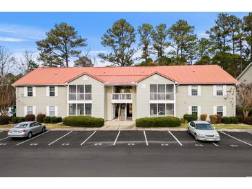 Two-story condo with covered porches, a red roof, mature landscaping, and parking spaces at 193 Charter Dr. # E7, Longs, SC 29568