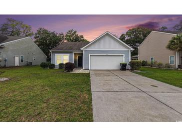 Charming single-story home featuring a two-car garage and a well-maintained lawn at sunset at 436 Cotton Grass Dr., Loris, SC 29569