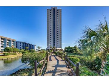 Exterior view of a condo complex with bridge access, landscaping, and water feature on a clear day at 5905 S Kings Hwy. # 1717, Myrtle Beach, SC 29575