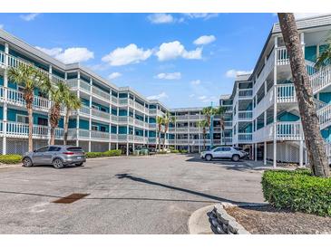 Brightly painted condominiums with white railings on the multiple decks offer coastal charm and curb appeal at 720 N Waccamaw Dr. # 202, Garden City Beach, SC 29576