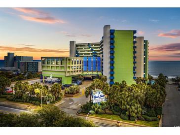 An exterior view of the Coral Beach Resort with a palm-lined entrance, and a sunset in the background at 1105 S Ocean Blvd. # 724, Myrtle Beach, SC 29577