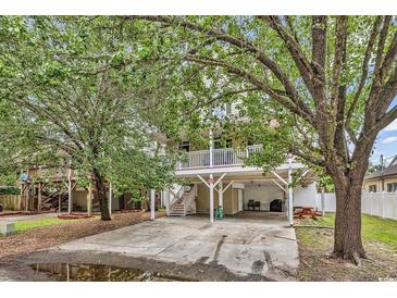 Exterior view of the home featuring a spacious driveway, well-maintained lawn, and mature trees at 17 South Oak Dr., Surfside Beach, SC 29575