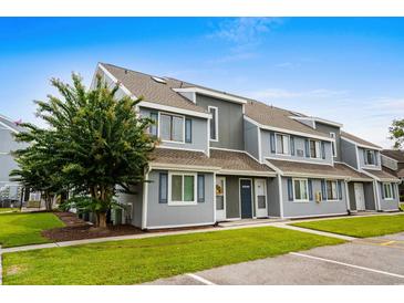Well-maintained townhome featuring gray siding, blue shutters, and manicured landscaping, creating a welcoming curb appeal at 1891 Colony Dr. # 15 J, Surfside Beach, SC 29575
