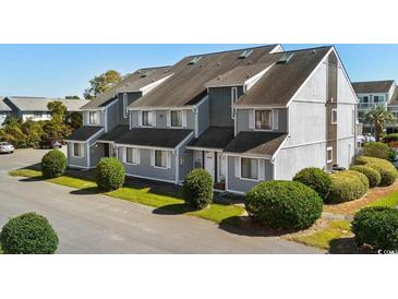 Charming townhouse with grey siding, black roof, and lush green landscaping on a sunny day at 3700 Golf Colony Lane # 6J, Little River, SC 29566