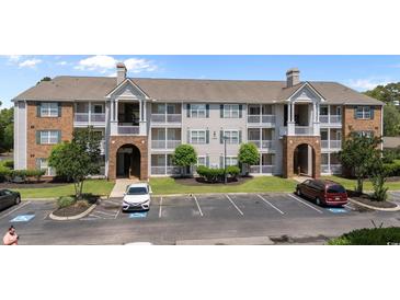 Low-angle shot of an apartment complex with brick and siding, showcasing well-maintained landscaping and ample parking at 3795 Hitchcock Way # 618, Myrtle Beach, SC 29577