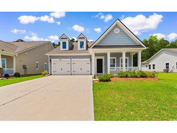 Charming light blue home boasts a two-car garage, inviting front porch, and manicured lawn at 739 Harrison Mill St., Myrtle Beach, SC 29579