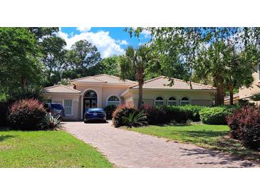 Charming single-story home featuring a tile roof, arched windows, and lush landscaping, creating curb appeal at 7614 Triana Ct., Myrtle Beach, SC 29572