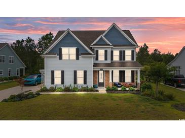 Charming two-story home with blue accents, covered porch, and a well-maintained lawn at sunset at 1325 Bermuda Grass Dr., Myrtle Beach, SC 29579