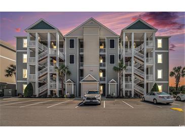 Attractive condo building with multiple floors, exterior staircases, and ample parking at dusk at 189 Ella Kinley Circle # 201, Myrtle Beach, SC 29588