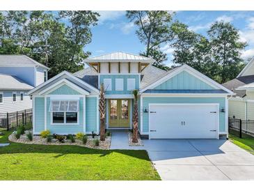 Charming, light blue single story home with a two car garage, lovely landscaping, and a sunny yellow front door at 1940 Indigo Cove Ln, Calabash, NC 28467