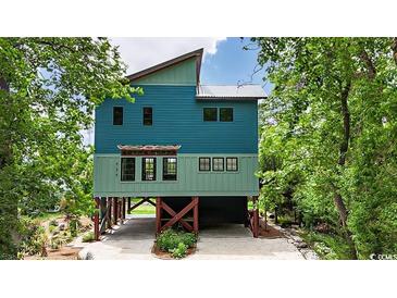 Two-story blue home featuring a unique design with wooden supports and lush green landscaping at 329 Kaufman St., Georgetown, SC 29440