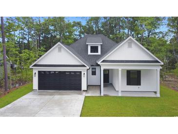 Charming home featuring white siding, a black garage door, and a cozy covered front porch at 4120 Whatuthink Rd., Myrtle Beach, SC 29588