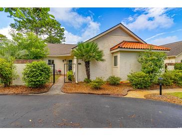 Charming home featuring a stucco exterior, red tile roof, well-manicured landscaping, and inviting front gate at 8 Martinique Dr., Myrtle Beach, SC 29572