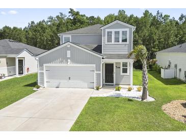 Charming two-story home featuring a well-maintained lawn, a two-car garage, and a mix of modern architectural design elements at 1146 Joywood Dr., Longs, SC 29568