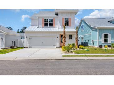 Charming two-story home featuring a light-colored exterior, lush landscaping and a two car garage at 1957 Indigo Cove Ln, Calabash, NC 28467