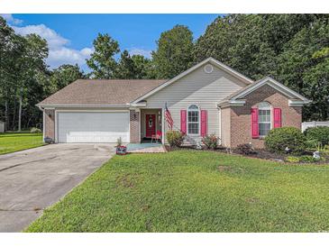 Charming single-story home featuring a well-manicured lawn, brick accents, red shutters, and an attached garage at 271 Sienna Dr., Little River, SC 29566
