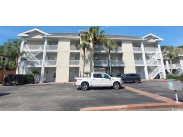 Three-story condo building with palm trees, parking, and white exterior paint in a coastal community at 400 Lands End Blvd. # 5304, Myrtle Beach, SC 29572