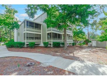 A charming multi-level home boasts screened-in porches and lush landscaping, enhancing its curb appeal in a tranquil setting at 415 Ocean Creek Dr. # 2189, Myrtle Beach, SC 29572