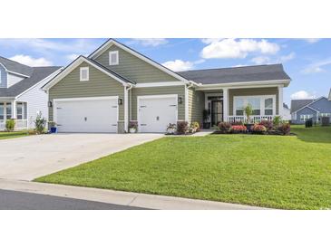 Charming home featuring an attached two car garage, green lawn and landscaping at 122 New Paradise Way, Myrtle Beach, SC 29588