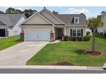 Charming single-story home featuring well-manicured lawn, two-car garage, and mature palm tree at 309 Rycola Circle, Surfside Beach, SC 29575