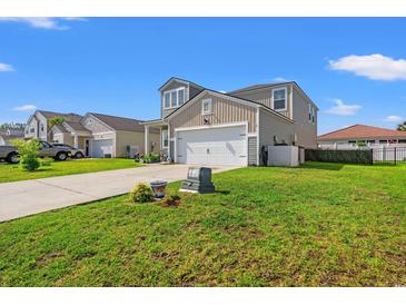 Two-story home featuring a two-car garage, a well maintained lawn, and neutral colored siding at 348 Hidden Cove Dr., Little River, SC 29566