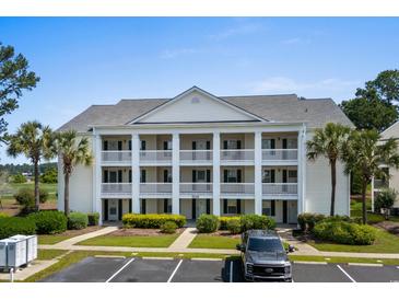 Inviting condo exterior featuring multiple balconies, lush landscaping, and ample parking spaces at 4940 Windsor Green Way # 301, Myrtle Beach, SC 29579