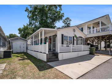 Charming white home featuring a welcoming porch and well-maintained landscaping at 6001-1833 S Kings Hwy., Myrtle Beach, SC 29575