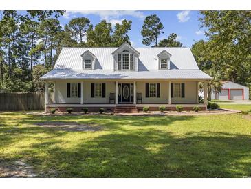 Charming one-story home featuring a metal roof, double-door entrance, and inviting front porch at 62 Warbler St., Georgetown, SC 29440