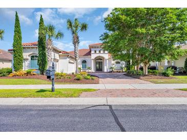Charming single-story home featuring a red tile roof, manicured landscaping, and a paved brick driveway at 7202 Seville Dr., Myrtle Beach, SC 29572