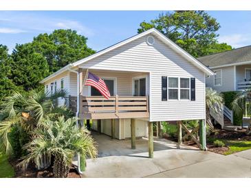 Charming coastal home on stilts with a cozy porch and American flag at 9679 Stillwater Ct., Myrtle Beach, SC 29572