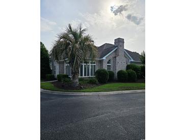 Charming home with a brick exterior, landscaped yard, and mature palm tree on a corner lot at 1426 Saint Thomas Circle # A 3, Myrtle Beach, SC 29577